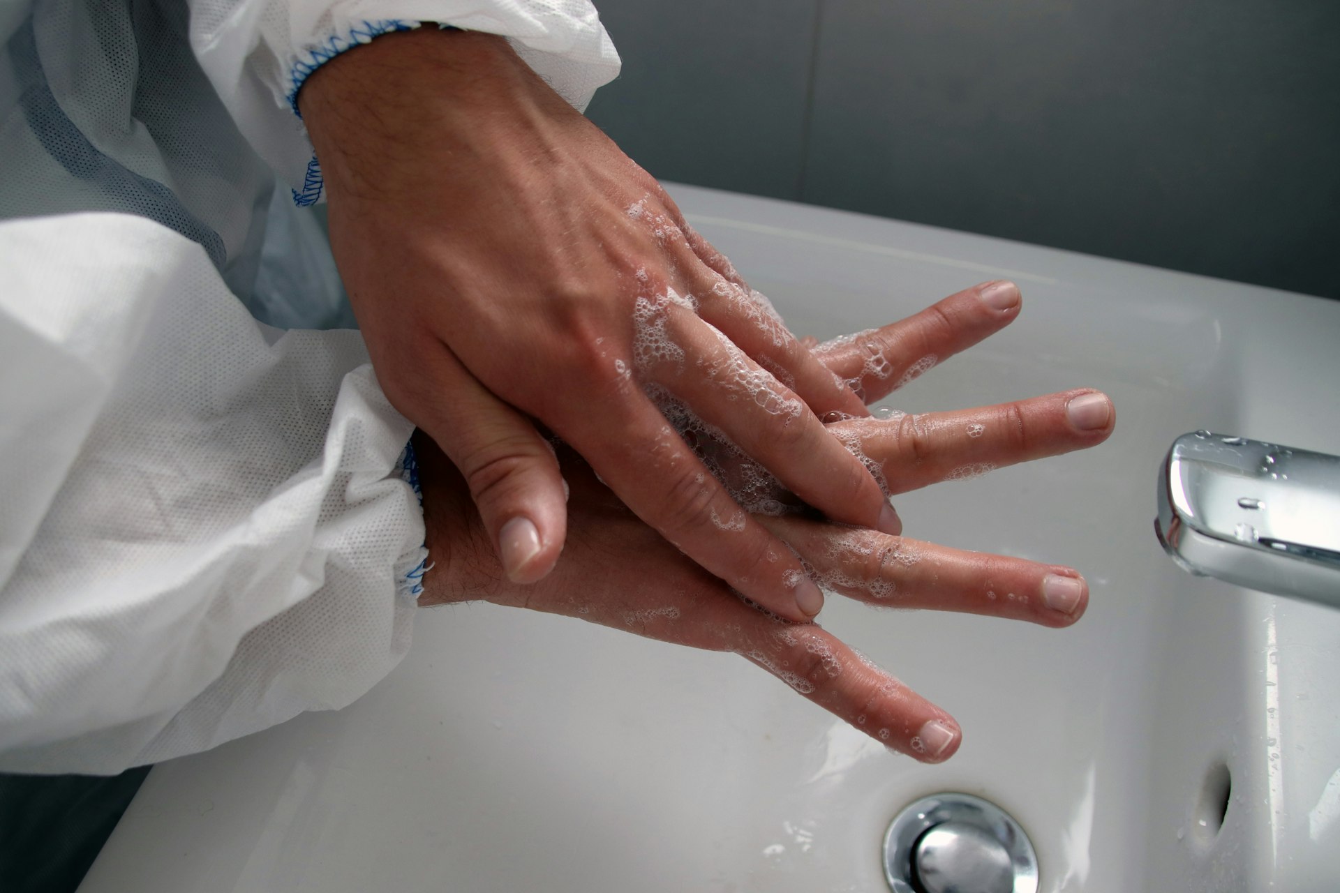 persons hand on white ceramic sink